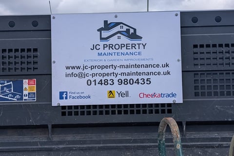 JC Property Maintenance business sign mounted on black equipment with contact details and social media icons